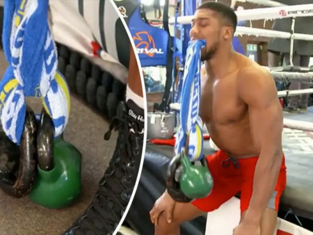 el boxeador Anthony Joshua entrenando su cuello con un kettlebell y una toalla