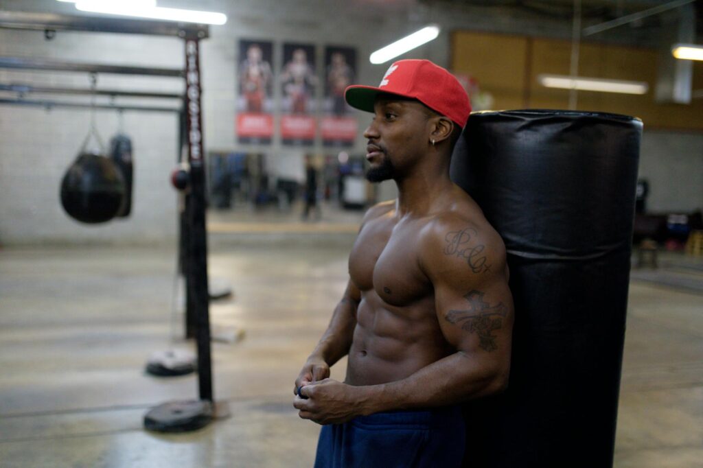 man leaning on black punching bag