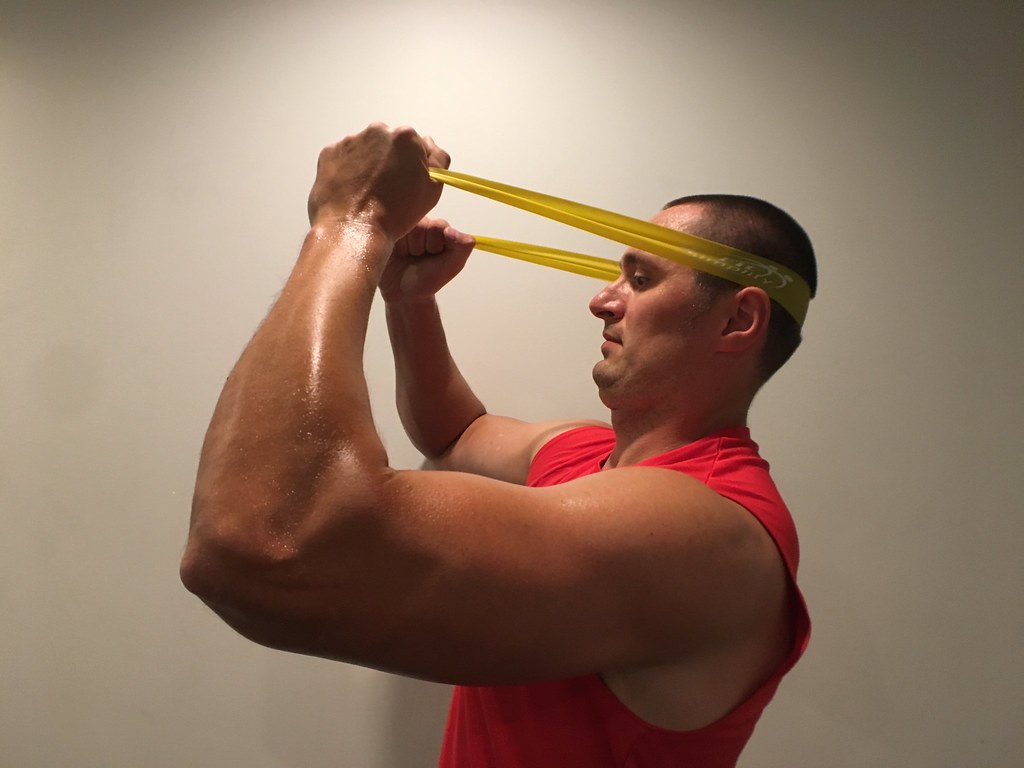 Un hombre realizando ejercicios isométricos de cuello con una goma elástica