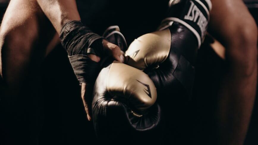 man in black tank top wearing blue and white boxing gloves